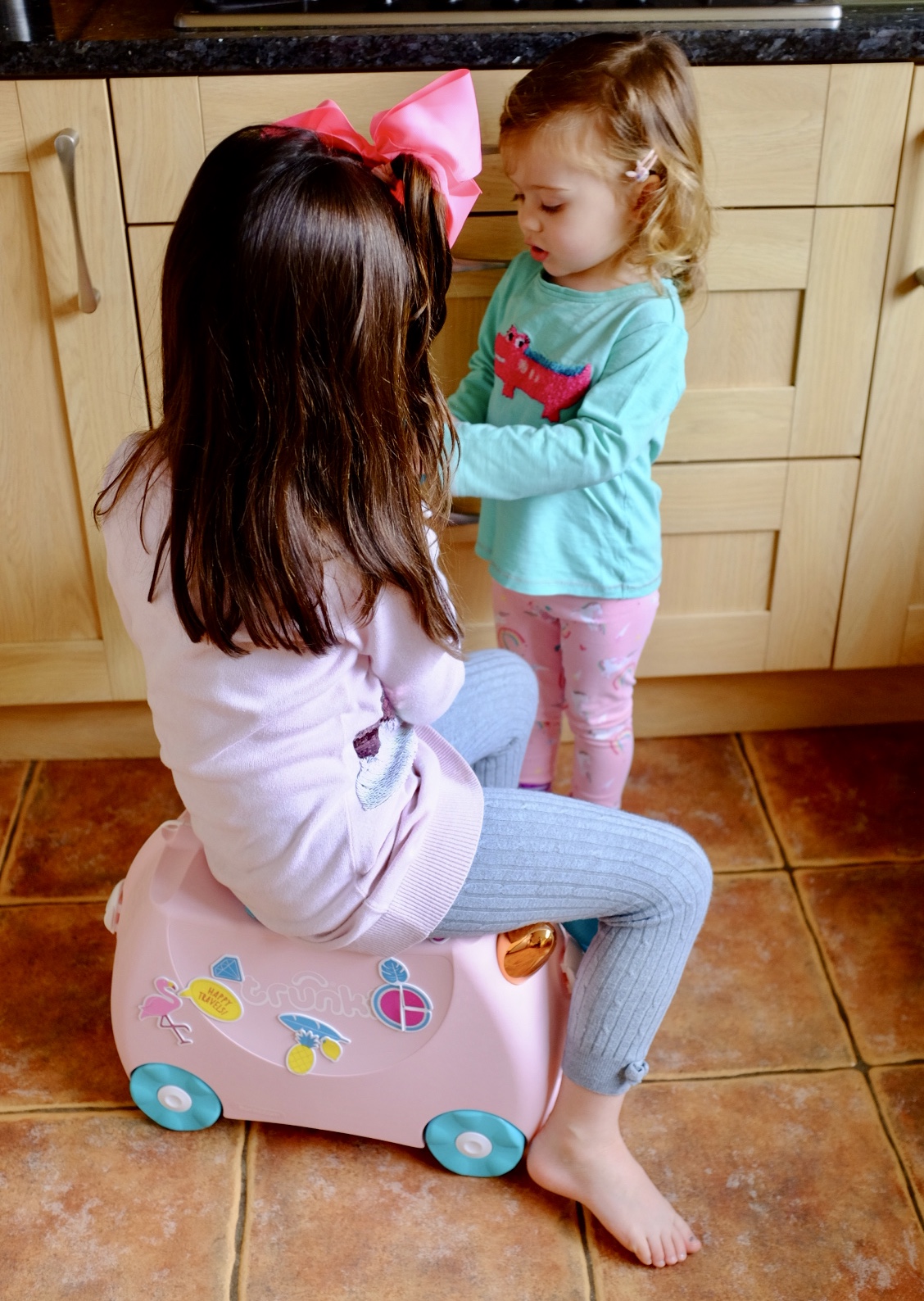 sisters playing with Flossi the Flamingo Trunki